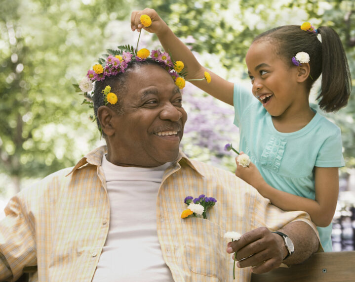child putting flowers in man's hair
